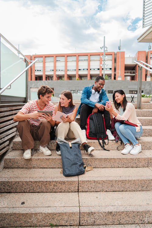 Preview: Vertical. Group of multiracial high school students talking on a staircase at university campus