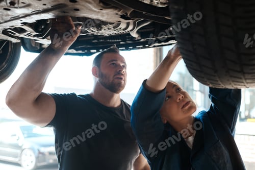 Preview: Shot of two mechanics working together under a lifted car
