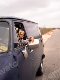 Preview: Portrait of a young man smiling through the window of his caravan during a road trip