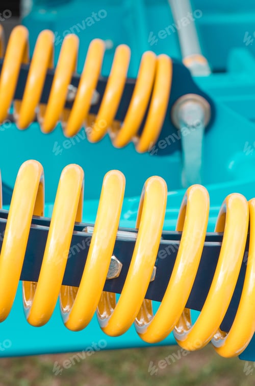 Preview: Big and hard steel yellow spring as part and detail of blue industrial or agricultural machine