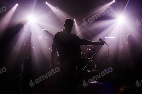 Preview: Singer performing with band on stage under purple lights