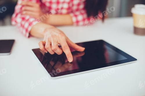 Preview: Young woman working with digital tablet. Finger touching the screen.
