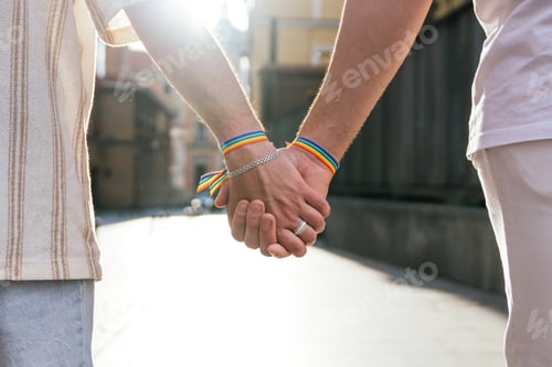 Preview: Two Unrecognizable Men, Hands Clasped, Strolling through City Streets, Wearing Rainbow Bracelets.