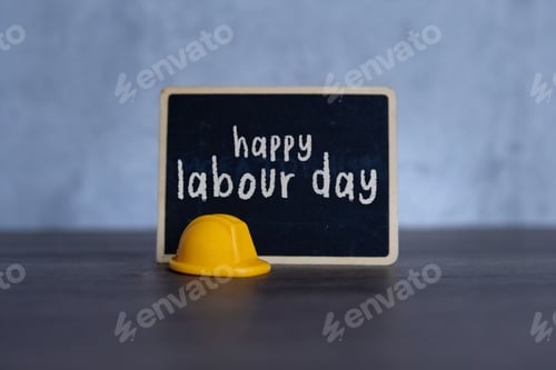 Preview: Yellow hard hat and chalkboard with text HAPPY LABOUR DAY.