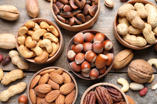 Preview: Flat lay composition with organic nuts on wooden background, top view. Snack mix