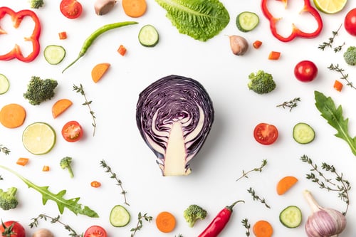 Preview: Top view of half of red cabbage in circle of cut vegetables isolated on white