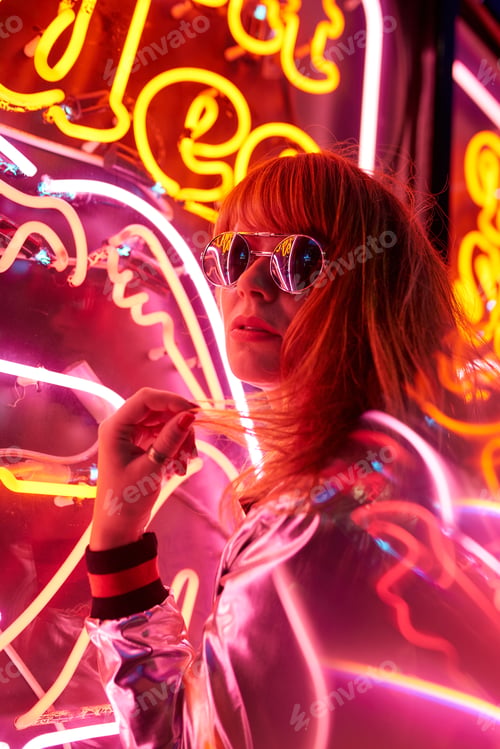 Preview: Portrait of woman with silver jacket and sunglasses in neon lights