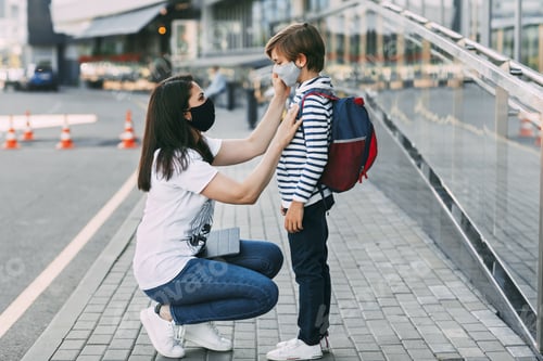 Preview: Mother adjusts her son's mask. A mother and child on their way to school
