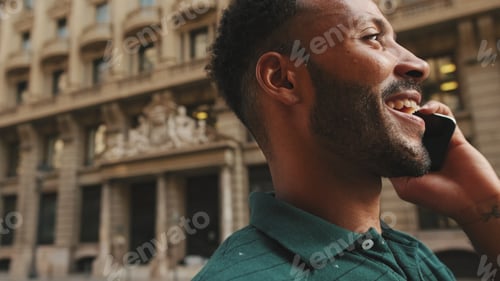 Preview: Young man talking on mobile phone while standing on the street next to the road
