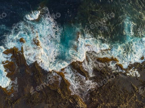 Preview: Aerial view of waves and sea crashing over volcanic coastline rocks