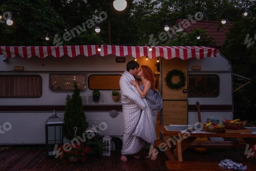 Preview: A young couple of happy lovers wrapped themselves in a white blanket by the trailer truck
