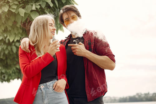 Preview: Stylish young couple with vape in a city