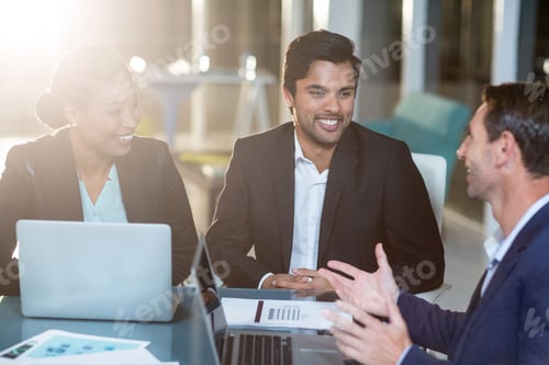 Preview: Businesswoman Discussing With Colleagues Over Laptop In Office