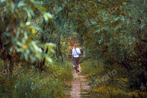 Preview: Young woman walking among trees