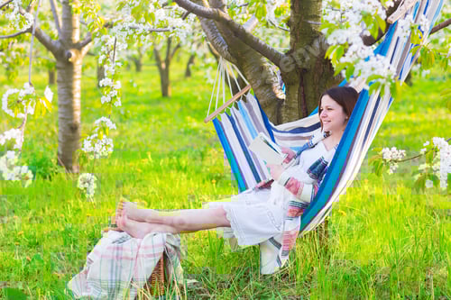 Preview: Beautiful pregnant woman in hammock in blooming garden