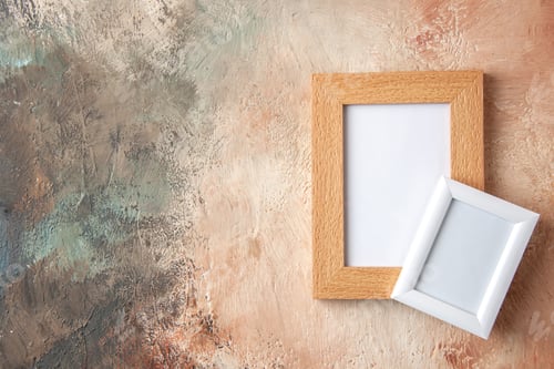 Preview: Close up view of small and big colorful photo frames on the left side hanging on pastel colors wall