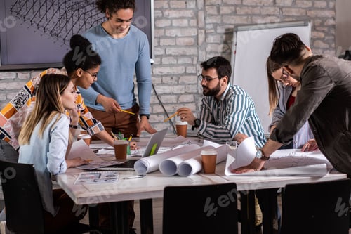 Preview: Group of modern business people in casual wear discussing architectural designs.