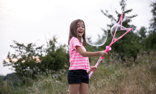 Preview: A little girl makes big soap bubbles in nature.