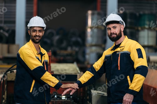 Preview: Engineers and the foreman stack and shake hands, symbolizing teamwork and success in the factory.