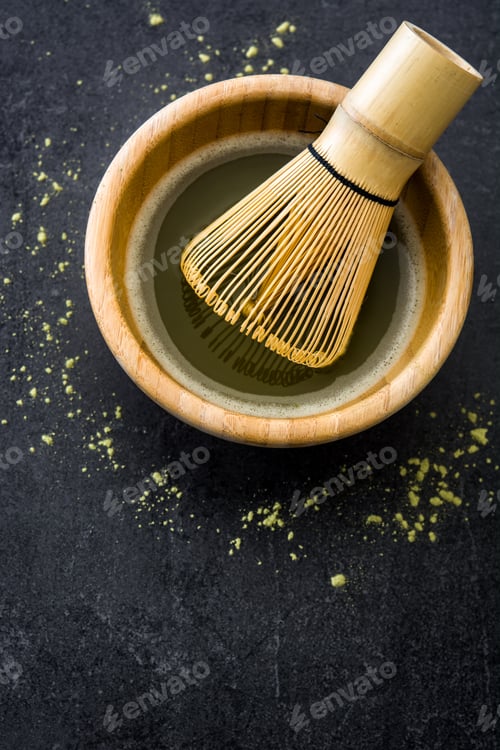 Preview: Bamboo whisk preparing matcha green tea in wooden bowl on dark background