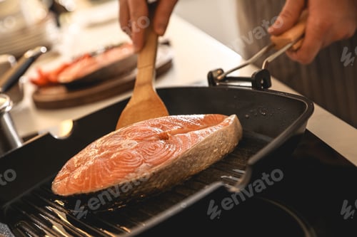 Preview: Man cooking fresh salmon steak in frying pan, closeup