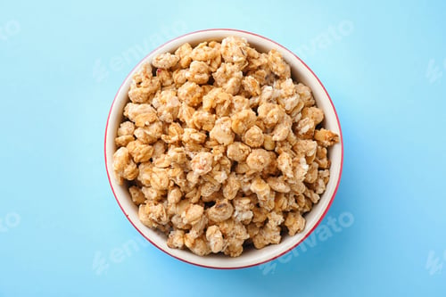 Preview: Bowl with healthy granola on light blue background, top view