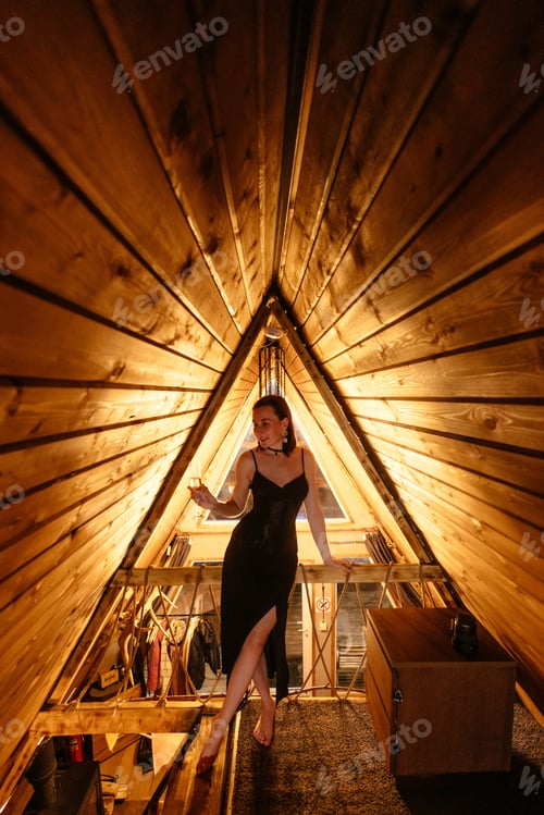 Preview: Woman standing in wooden loft with sloped ceiling and warm lighting
