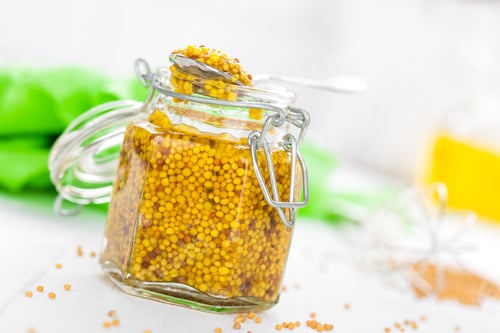 Preview: Mustard in glass jar on white wooden table closeup. Dijon mustard