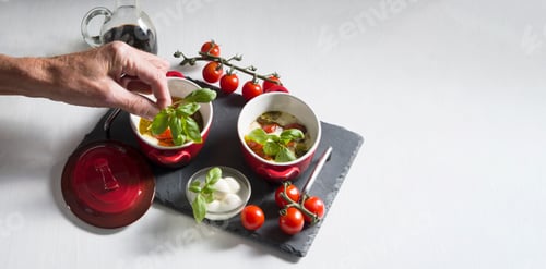 Preview: Italian caprese salad, baked cherry tomatoes, mozzarella and basil on a white table, still life