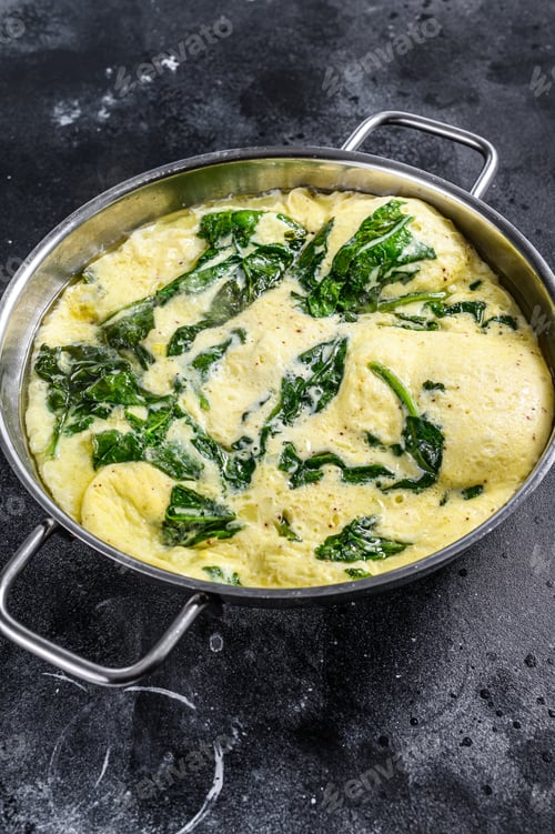 Preview: Italian Spinach and Cheese Omelet in a pan. Black background. Top view