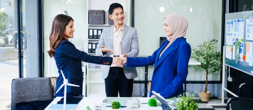 Preview: Three businesspeople convene at a desk with handshakes. clean energy, waste reduction