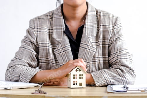 Preview: Person Gently Places Their Hands On Miniature House Model, Symbolizing Property Protection