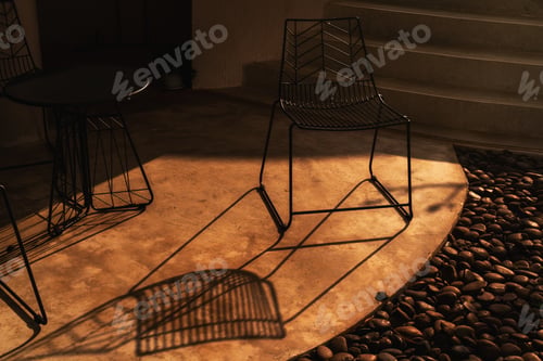 Preview: Modern Metal Chair Casting Shadow on Concrete Patio at Sunset