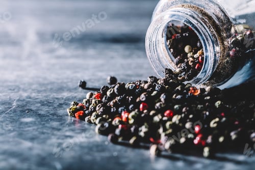 Preview: Grains of pepper spilling out of glass jar.