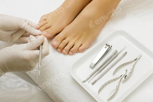 Preview: Pedicure master work. Close up of female nails and pedicurist hands in gloves with special tools.