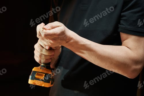 Preview: Hands of a caucasian worker close-up install a drill in an electric drill driver with a battery