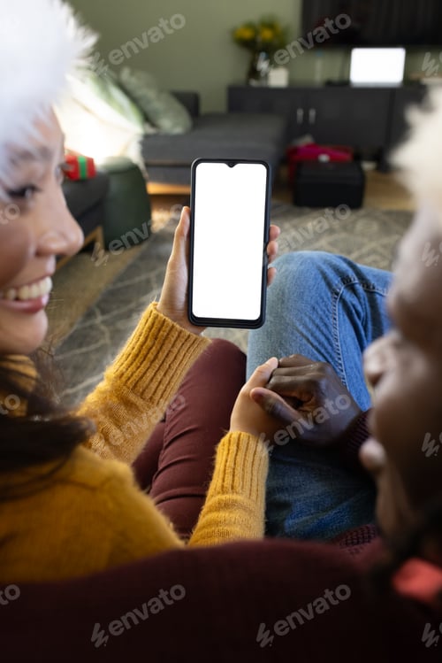 Preview: Happy diverse couple in christmas hats having smartphone video call, copy space screen