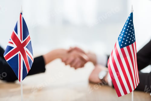 Preview: selective focus of flags of usa and united kingdom near diplomats shaking hands