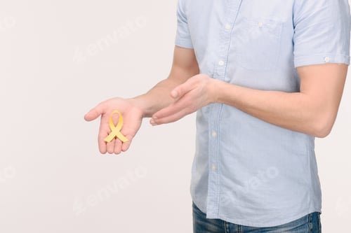 Preview: cropped shot of man showing Childhood Cancer Awareness yellow ribbon isolated on white