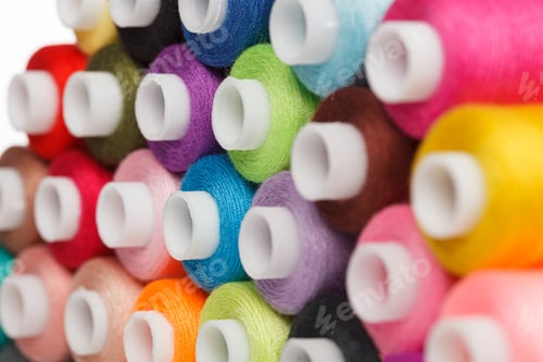 Preview: multi-colored spools of sewing thread on a white background