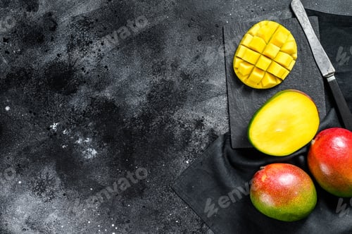 Preview: Ripe mango fruit, cut into cubes. Black background. Top view. Copy space