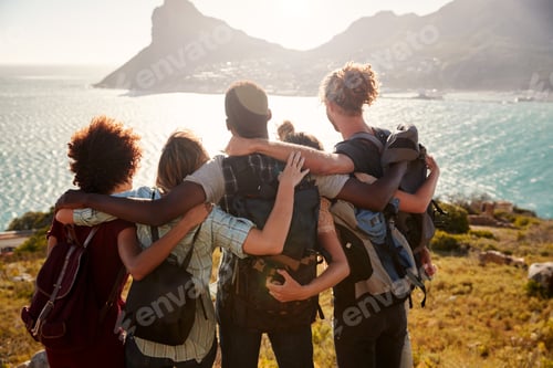 Preview: Millennial friends on a hiking trip reach the summit and embrace, admiring the view, back view