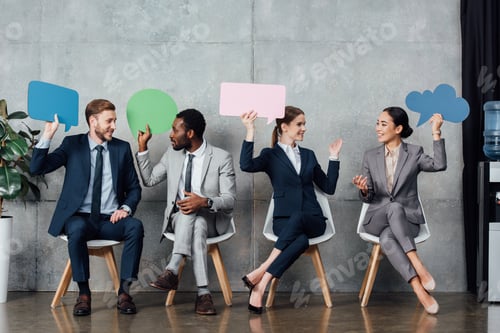 Preview: happy multiethnic businesspeople holding speech bubbles and thought bubble while sitting in waiting