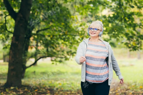 Preview: Beautiful woman, senior, running in headphones, walking in the park, playing sports