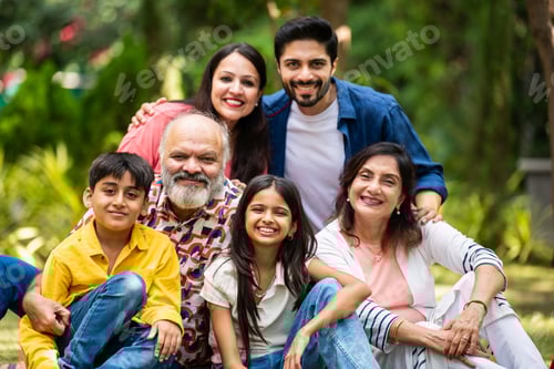 Preview: Indian family of three generations smiling and bonding outdoors on green park lawns