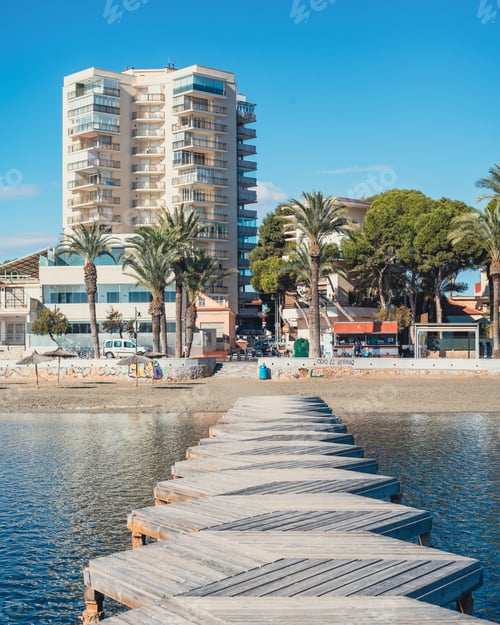 Preview: the boardwalk on the beach leads to a hotel and palm trees