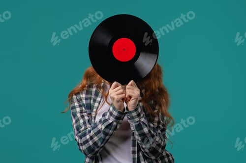 Preview: Positive red haired woman with vinyl record disc on blue. Hobby, music lover, collection, nostalgia