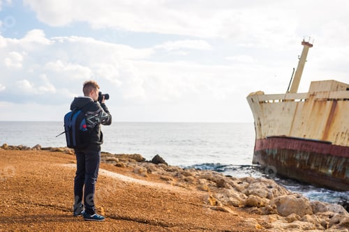 Preview: Young photographer on the beach. Traveler photographer with digital camera.