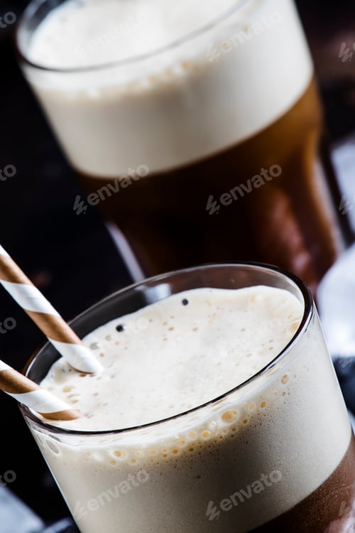 Preview: Cold frothy frappe coffee in large glasses on brown background, selective focus