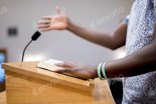Preview: Closeup shot of a person reading the bible on a wooden stand in the church with blurred background